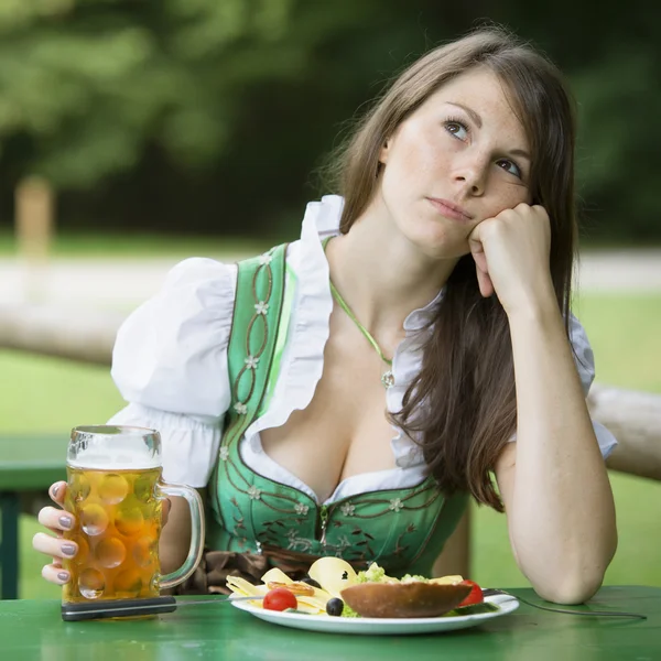 Femme dans dirndl assis à la bière jardin et l'air ennuyé — Photo