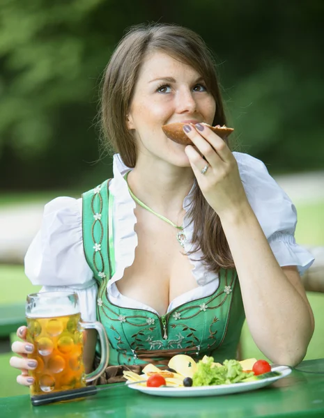 Beierse vrouw in dirndl eten bij biertuin — Stockfoto