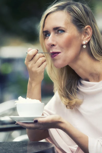 woman sitting outside at cafe and drinking coffee