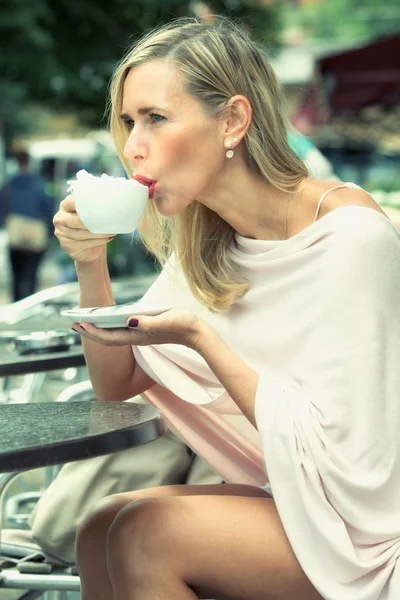 Frau sitzt draußen im Café und trinkt Kaffee — Stockfoto