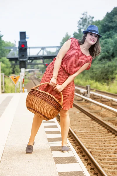 Mujer joven de pie en el andén y esperando el tren — Foto de Stock