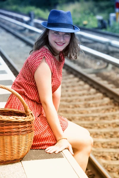 Giovane donna seduta sul binario alla stazione ferroviaria — Foto Stock