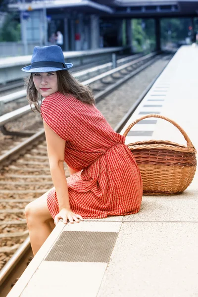 Jovem mulher sentada na plataforma na estação de trem — Fotografia de Stock