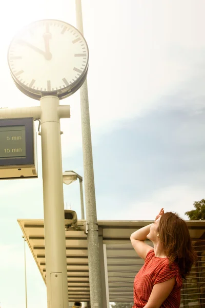 Jonge vrouw kijken naar klok bij treinstation — Stockfoto