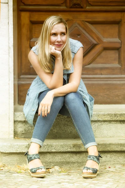 Vrouw zit voor houten deur op stappen — Stockfoto