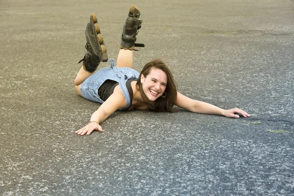 Femme avec des patins à roulettes couché dans la rue et rit — Photo