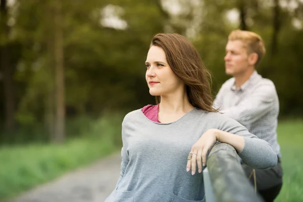 Man and woman leaning against fence in nature — Stock Photo, Image