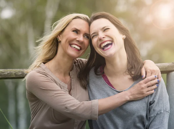 Två kvinnan skrattar och kramar varandra utomhus — Stockfoto