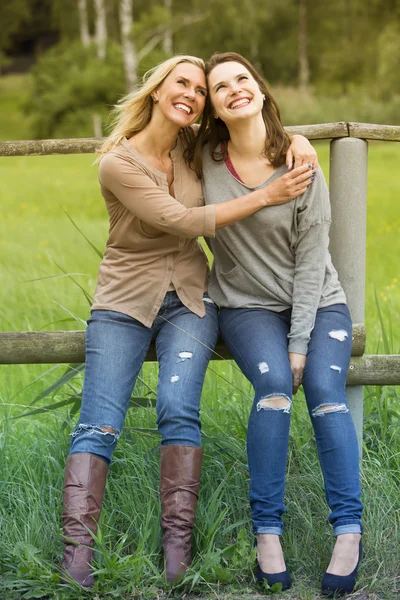 Dos mujeres sentadas en la valla y riendo — Foto de Stock