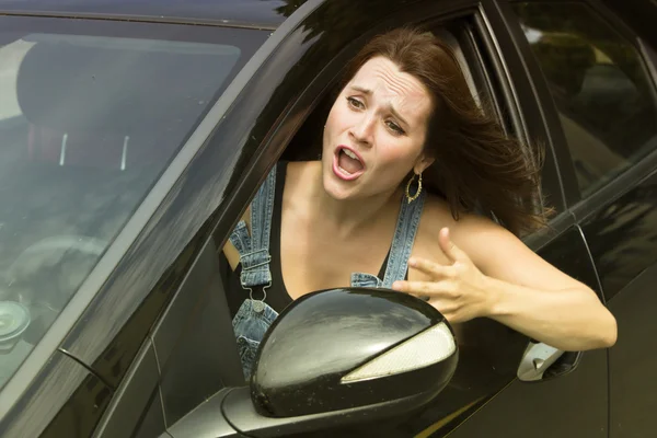 Jonge vrouw zitten in de auto en kijkt boos — Stockfoto