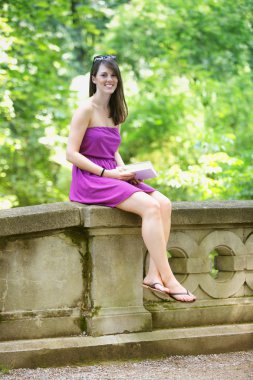 parkta oturan ve kitap okuma genç kadın