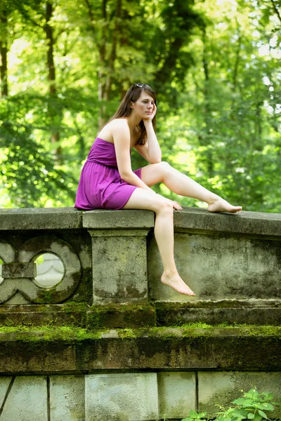 Jeune femme assise dans le parc regardant triste — Photo