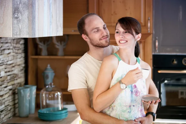 Joven pareja de pie en la cocina y abrazos —  Fotos de Stock