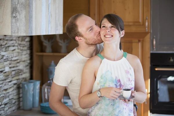 Hombre besando joven mujer en cocina —  Fotos de Stock