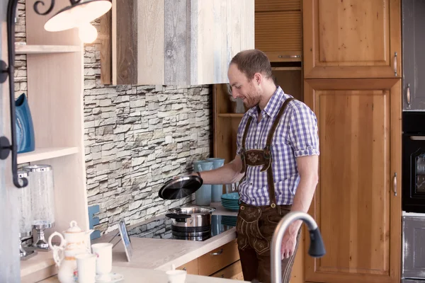 Uomo in abiti bavaresi tradizionali stand ng in cucina — Foto Stock