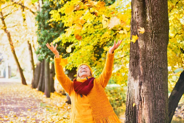Sonbaharda Yaşlarında Mutlu Bir Kadın Dökülen Yapraklarla Oynuyor — Stok fotoğraf