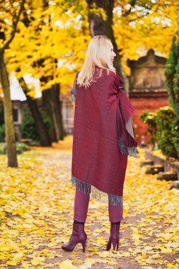 Sonbaharda bir parkta dışarıda duran sarışın kadının arkası.