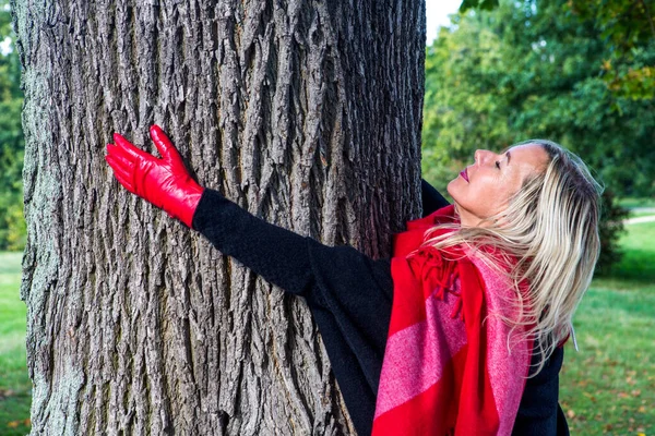 Blondynka Tce Przytula Drzewo Czerwonych Rękawiczkach Jesienią — Zdjęcie stockowe