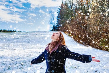 Genç esmer kadın karın üzerinde duruyor ve kollarını açıyor.