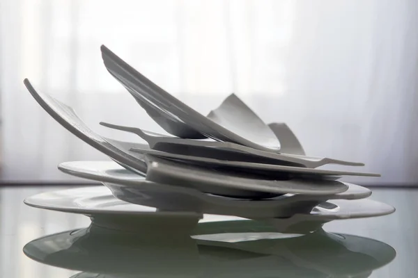 pile of broken white plates on a glass table