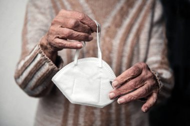 Yüz maskesi tutan yaşlı kadınların yakın plan fotoğrafları.