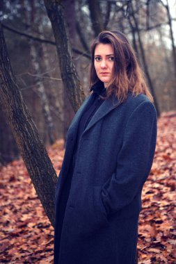 Sonbaharda bir ormanın ortasında tek başına duran genç bir kadın.