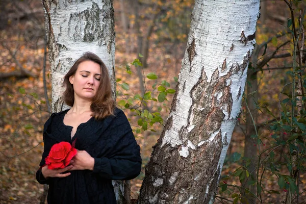 Portret Smutnej Brunetki Kobieta Czarnej Sukience Gospodarstwa Czerwony Kwiat Lesie — Zdjęcie stockowe