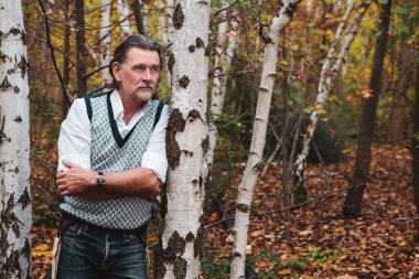 50 'li yaşlarda ormanda duran yakışıklı bir adamın portresi.