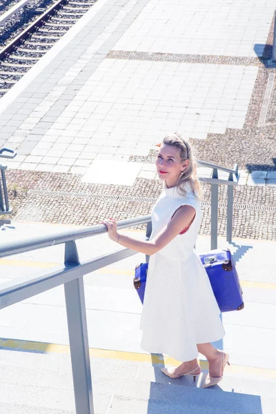 Larında Beyaz Elbiseli Sarışın Bir Kadın Tren Istasyonunda Elinde Bavulla — Stok fotoğraf