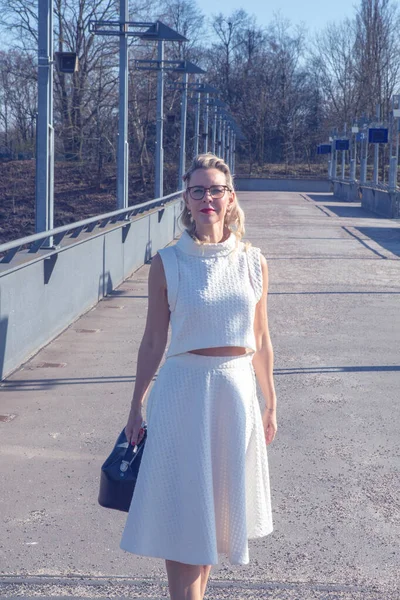 40多岁的金发女人穿着白衣站在外面阳光灿烂的大街上 — 图库照片