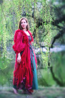 Doğada yalınayak yürüyen kırmızı elbiseli güzel esmer kadın.