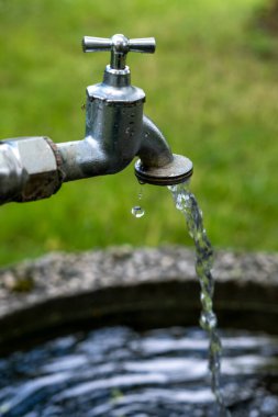 Bahçede akan suyu olan bir musluğun yakın çekimi.