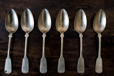 Altı gümüş kaşık tahta masanın üzerinde yatıyor.