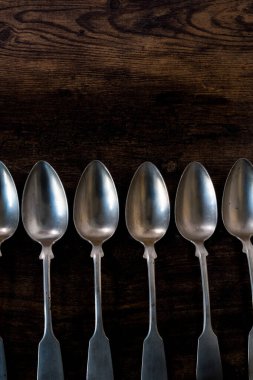 close-up of six silvver spoons lying in a row on wooden table