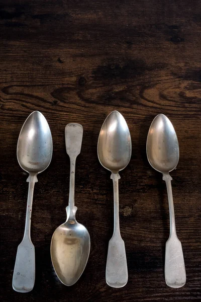 four spoons lie on a table while one lies the other way around