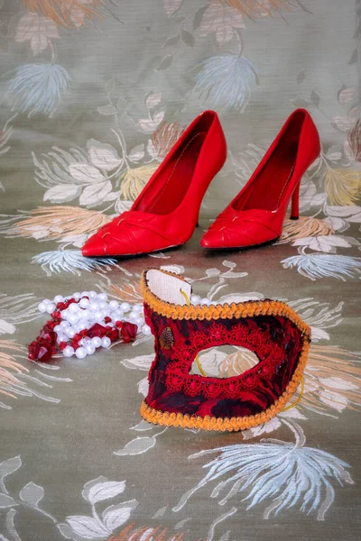 花の背景に赤細かく刺繍されたマスク ネックレス ハイヒールのクローズアップ — ストック写真