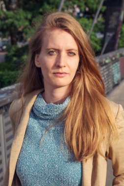 Güzel sarışın bir kadının portresi. Dışarıda dikiliyor ve dalgın bakıyor.