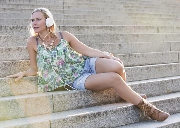 Mulher sentada nas escadas com fones de ouvido — Fotografia de Stock