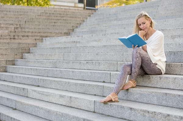 Женщина сидит на лестнице и читает книгу — стоковое фото