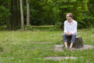 bir ağaç kütüğü oturan genç adam