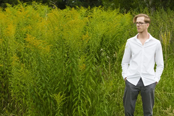 Çiçekler arasında duran genç adam — Stok fotoğraf