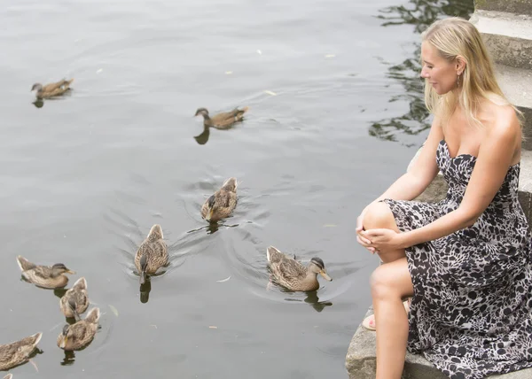 Woman at a lake with ducks — Stock Photo, Image
