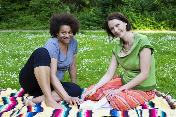 Duas mulheres no parque com um livro — Fotografia de Stock