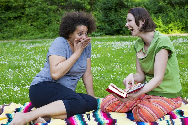 Två kvinnor i parken med en bok — Stockfoto