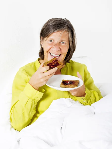 Mujer en la cama con tostadas — Foto de Stock