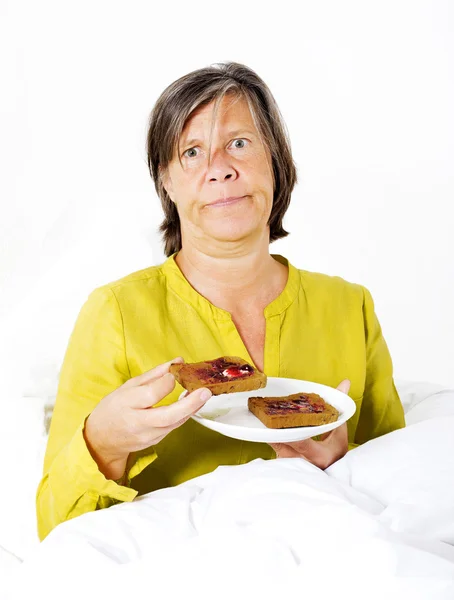 Vrouw in bed met toast — Stockfoto