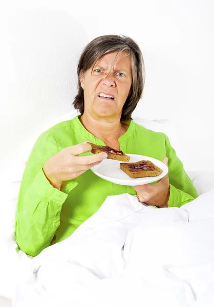 Vrouw in bed met toast — Stockfoto