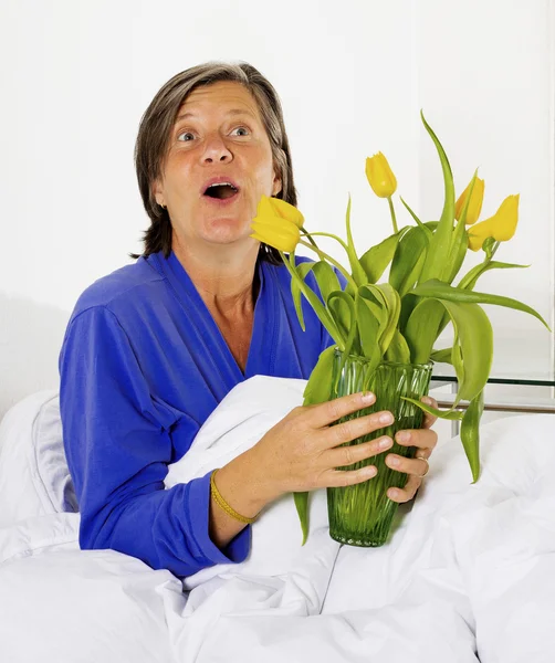 Kvinna i sängen med blommor — Stockfoto