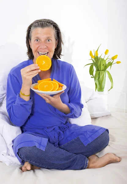 Žena v posteli s pomeranči — Stock fotografie