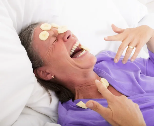 Mulher na cama com fatias de banana nos rostos — Fotografia de Stock